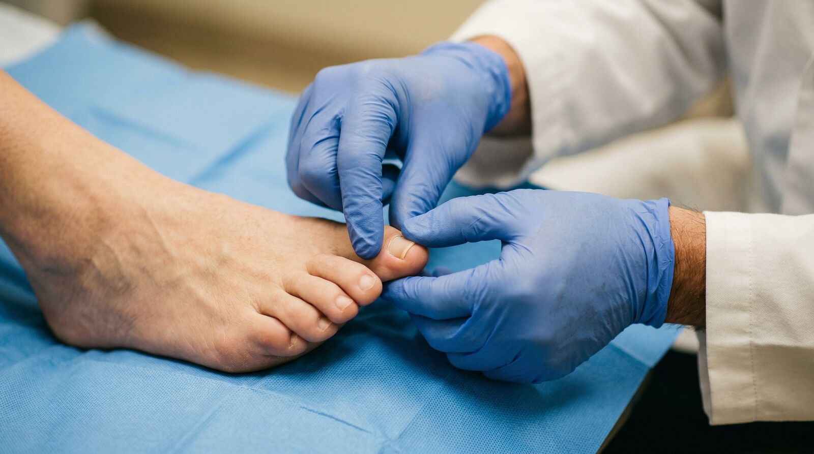 Doctor's gloved hands carefully examining a patient's big toe